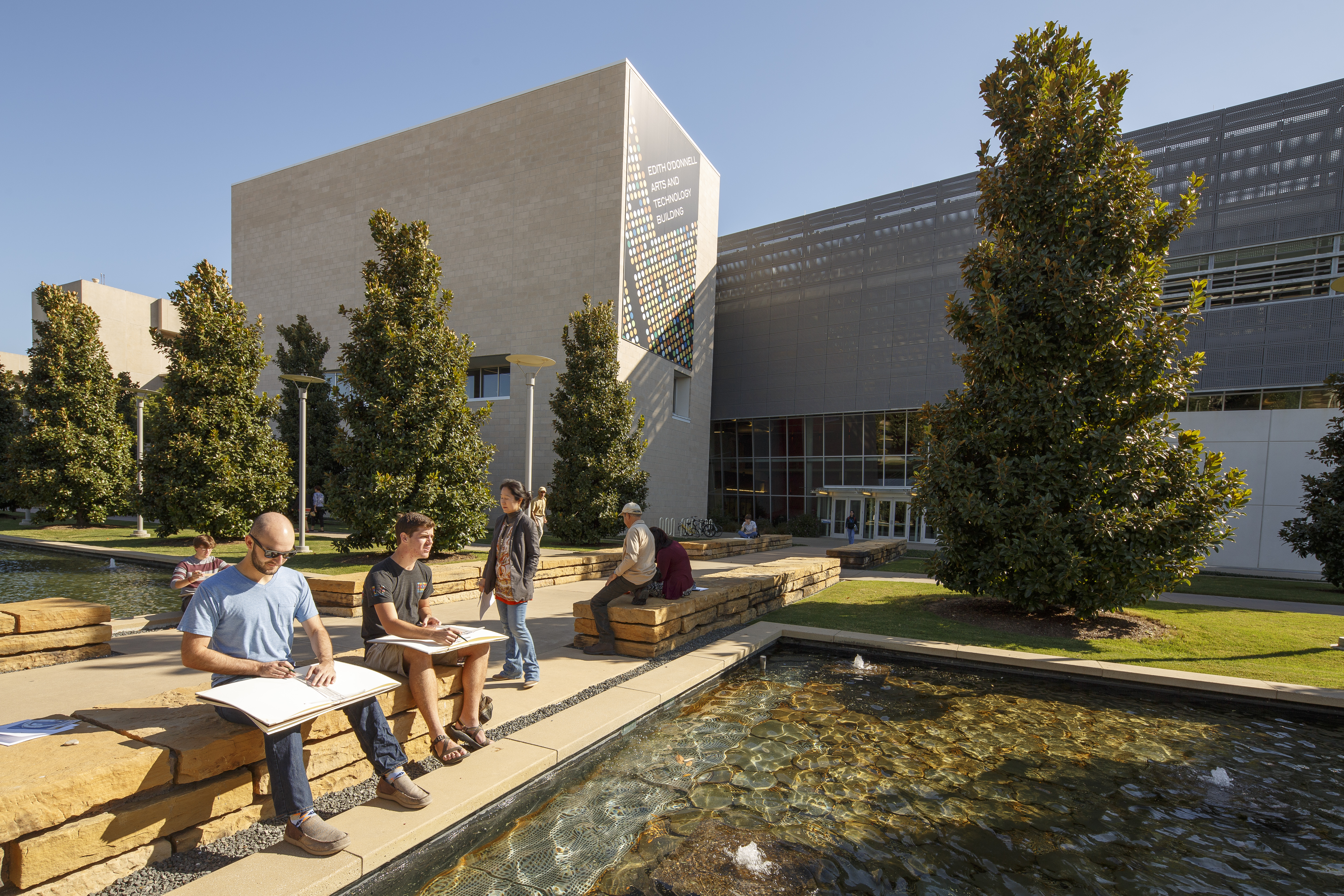 Art students sit on stone benches as they work on a class project