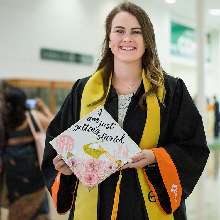 Grad holding cap with pink flowers that says I am just getting started