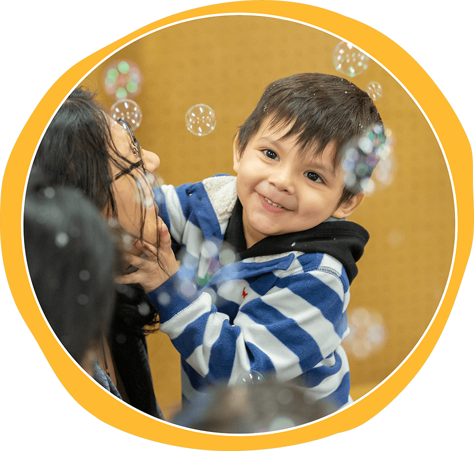 A smiling child playing with bubbles